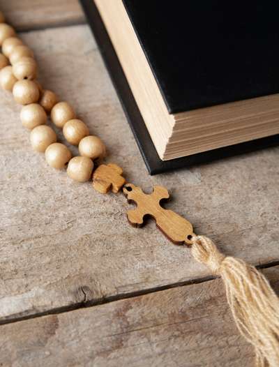 Bible fermée sur laquelle est posée un rosaire et une croix en bois