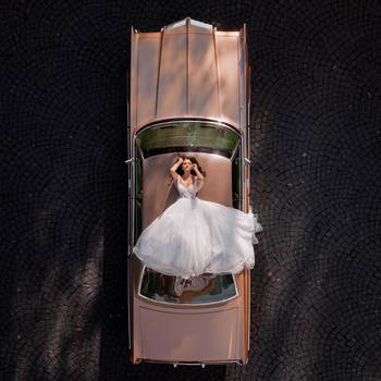 Vue aérienne d'une mariée sur une voiture ancienne prise par un drone